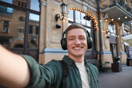 Smiling man in headphones taking selfie outdoorsの写真素材