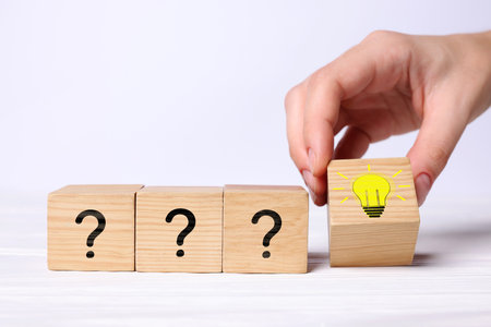Idea concept. Woman putting cube with illustration of light bulb to other ones with question marks...