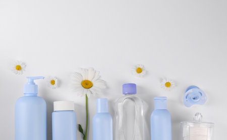 Different skin care products for baby in bottles and daisies on white background, flat lay. Space for textの写真素材