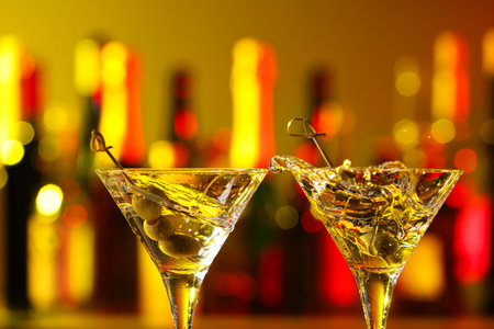 Clinking martini glasses with splashing cocktail and olives in bar, closeupの写真素材
