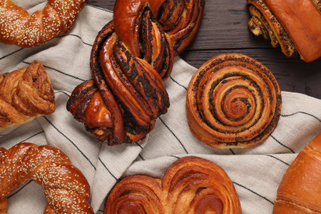 Different tasty freshly baked pastries on wooden table, flat lay