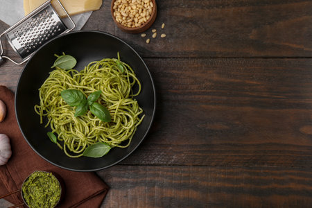 Delicious pasta with pesto sauce and basil on wooden table, flat lay. Space for textの写真素材