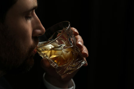 Man drinking whiskey on black background, closeup. Space for textの写真素材
