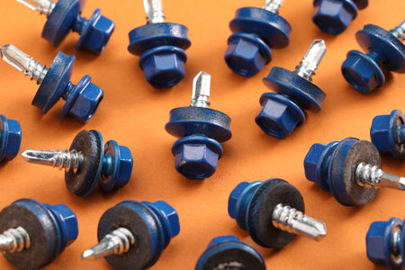 Blue self-tapping screws on orange background, closeupの写真素材