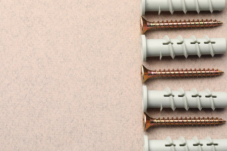 Many metal screws and dowels on beige textured table, flat lay. Space for textの写真素材