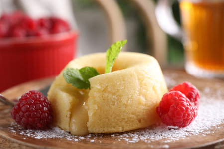 Tasty vanilla fondant with white chocolate and raspberries on wooden board, closeupの写真素材