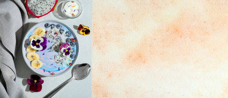 Smoothie bowl with pitahaya, banana and blueberries on beige textured table, flat lay. Banner design with space for textの写真素材