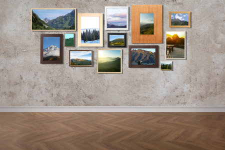 Many beautiful landscapes in frames on gray textured wall in roomの写真素材
