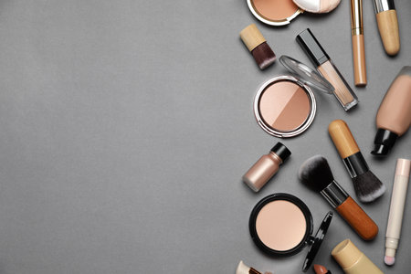 Face powders and other makeup products on gray background, flat lay. Space for textの写真素材