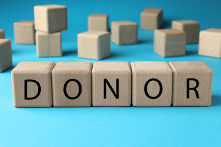 Wooden cubes with word Donor on light blue backgroundの写真素材