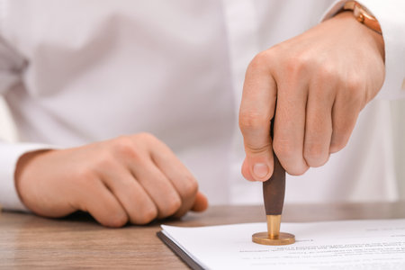 Man stamping document at wooden table, closeupの写真素材