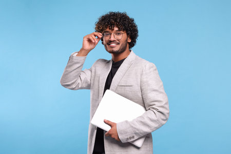 Smiling man with laptop on light blue background. Space for textの写真素材