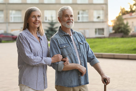 Senior man with walking cane and mature woman outdoorsの写真素材