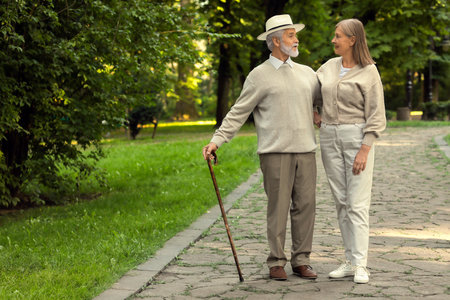 Senior man with walking cane and mature woman in park. Space for textの写真素材