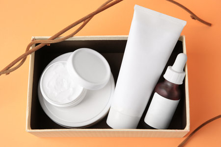 Box with cosmetic products and decorative twigs on orange background, above viewの写真素材