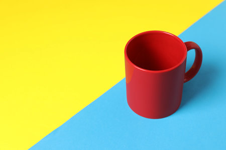 One red ceramic mug on color background. Space for textの写真素材