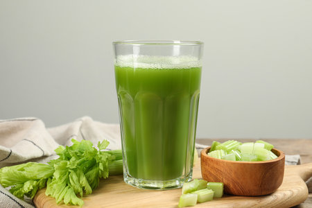 Glass of celery juice and fresh vegetables on tableの写真素材