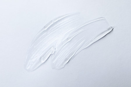 Swatches of cosmetic gel on white background, top view