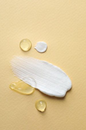 Samples of transparent gel and white cream on yellow background, flat layの写真素材