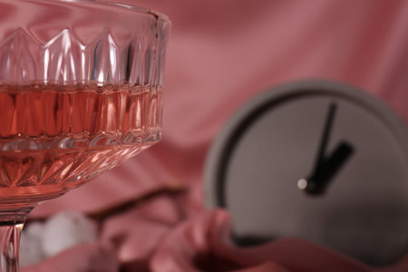 Glass of alcohol drink on pink cloth, closeup. Space for textの写真素材