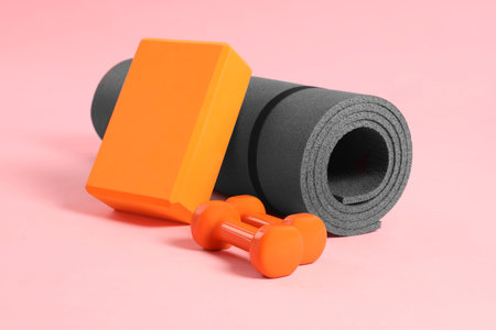 Gray exercise mat, yoga block and dumbbells on pink backgroundの写真素材