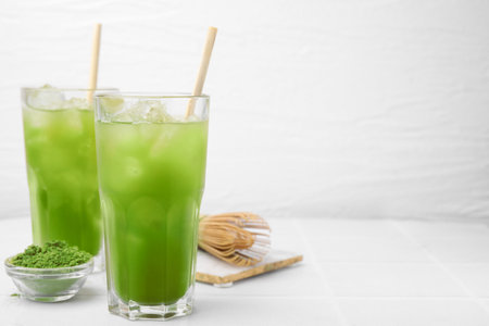 Delicious iced green matcha tea, powder and bamboo whiskey on white tiled table, space for textの写真素材