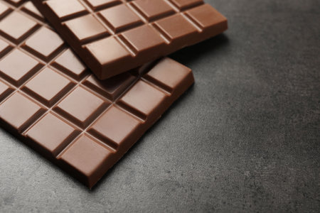 Delicious milk chocolate bars on black table, closeup. Space for textの写真素材