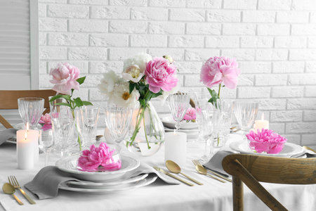 Stylish table setting with beautiful peonies in dining roomの写真素材