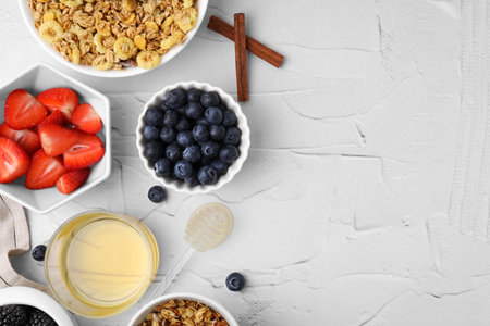Tasty oatmeal, honey and fresh berries on white textured table, flat lay with space for text. Healthy breakfastの写真素材