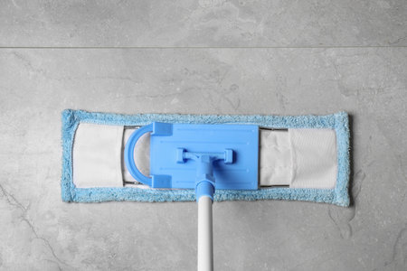 Cleaning gray marble floor with mop indoors, top view