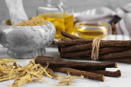 Dried sticks of licorice roots and shavings on white table, closeupの写真素材