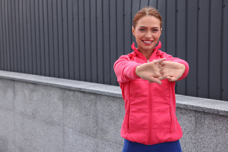 Beautiful woman in gym clothes doing exercises on street, space for textの写真素材