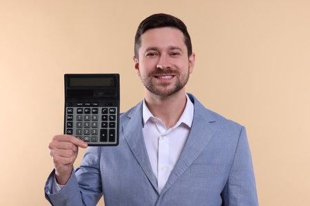 Happy accountant with calculator on beige backgroundの写真素材