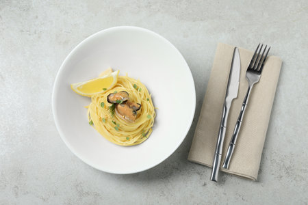 Tasty capellini with mussels and lemon served on light gray table, flat lay. Exquisite presentation of pasta dishの写真素材
