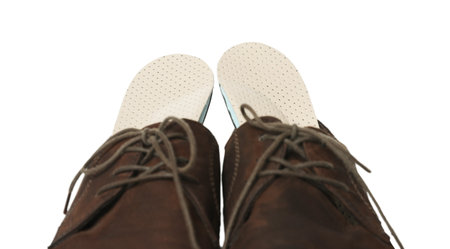 Orthopedic insoles in shoes on white background, closeup