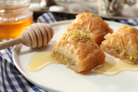 Delicious sweet baklava with pistachios and honey on table, closeup