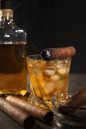 Cigars and whiskey on gray table against black backgroundの写真素材