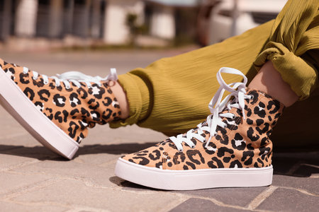 Woman wearing sneakers with leopard print outdoors, closeup