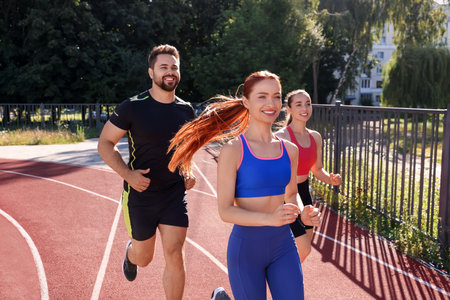 Group of people running at stadium on sunny day