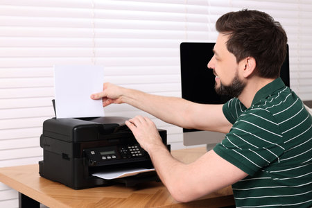 Man using modern printer at wooden table indoorsの写真素材