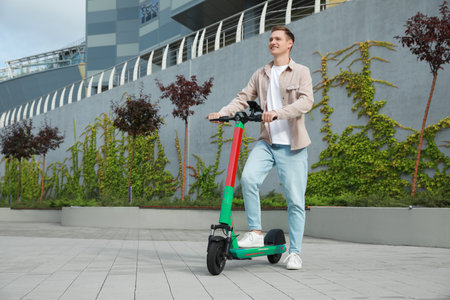 Happy man with modern electric kick scooter on city street, space for textの写真素材