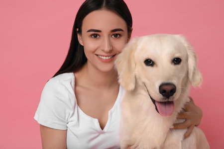 Happy woman with cute Labrador Retriever dog on pink background. Adorable pet