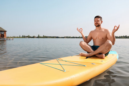 Man practicing yoga on SUP board on river