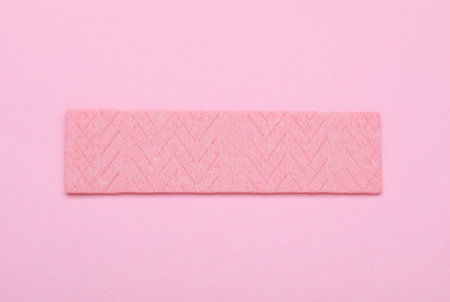 Stick of tasty chewing gum on pink background, top view