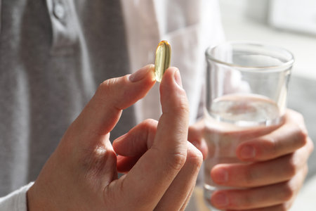 Man with glass of water and pill on blurred background, closeupの写真素材