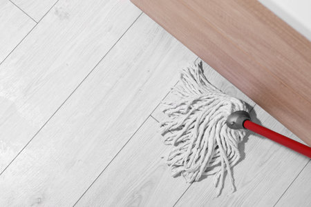 Cleaning dirty parquet floor with mop indoors, above view. Space for textの写真素材
