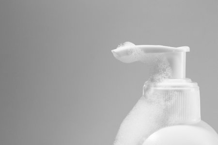Dispenser with cleansing foam on light gray background, closeup and space for text. Cosmetic productの写真素材