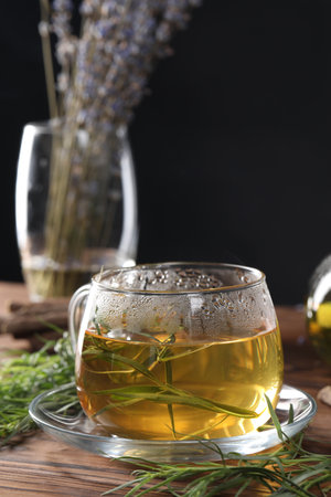 Homemade herbal tea and fresh tarragon leaves on wooden tableの写真素材