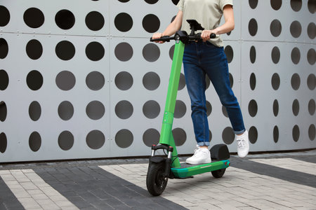 Woman riding modern electric kick scooter on city street, closeup. Space for textの写真素材