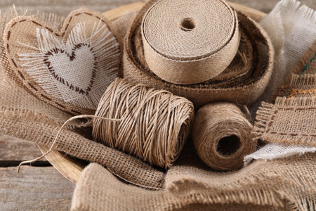 Pieces of burlap fabric and spools of twine on wooden table, closeupの写真素材